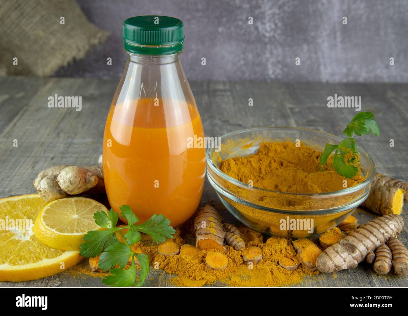 Turmeric juice in a bottle, lemon, orange and turmeric powder on a