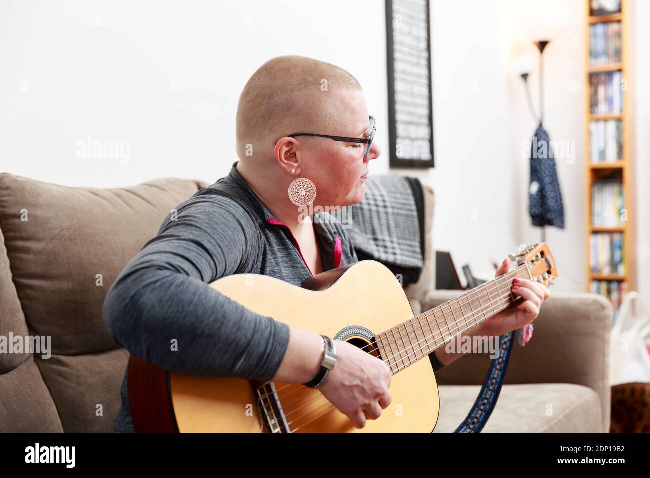 Woman playing guitar on sofa Stock Photo