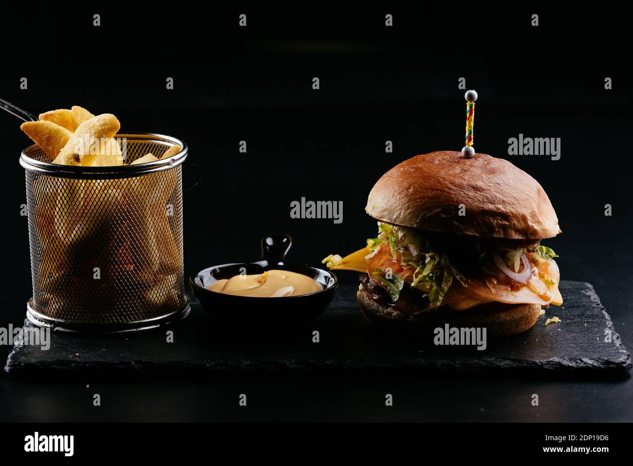 Burger, potatoes, sauce on a black background Stock Photo