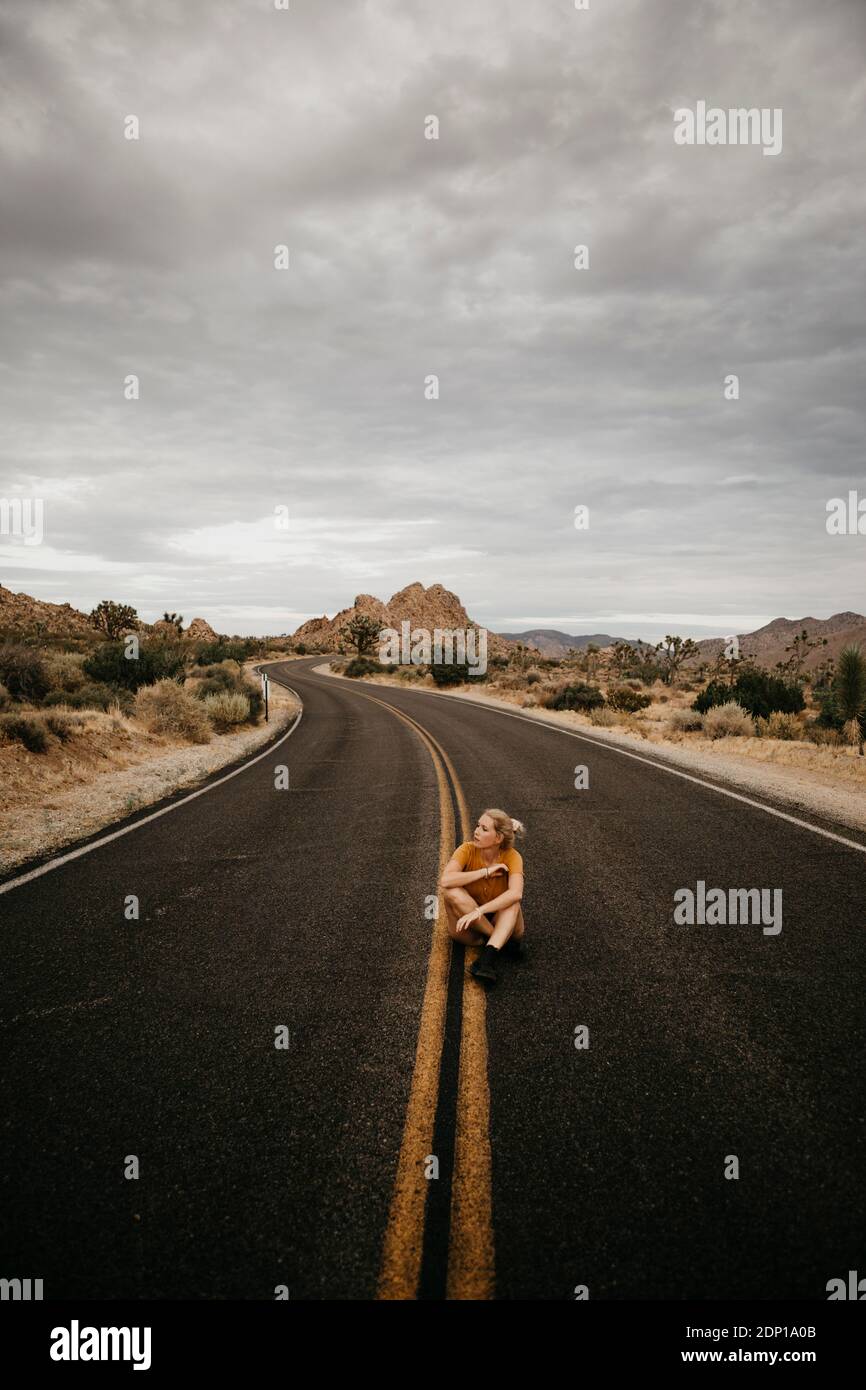 Woman sitting on road, Joshua Tree National Park, California, USA Stock Photo