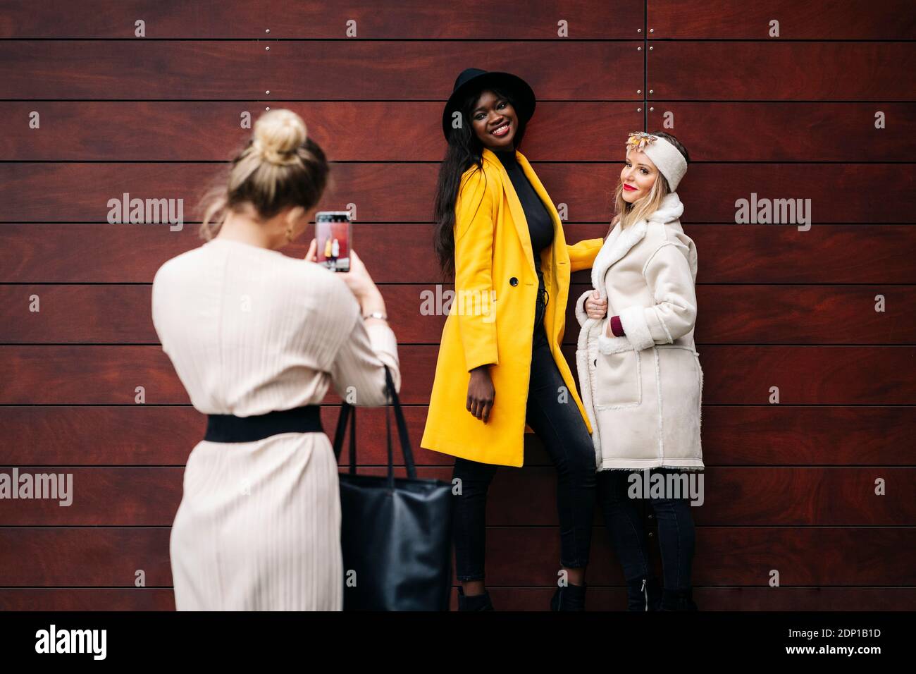 Two fashionable women posing for a photo at a wooden wall Stock Photo