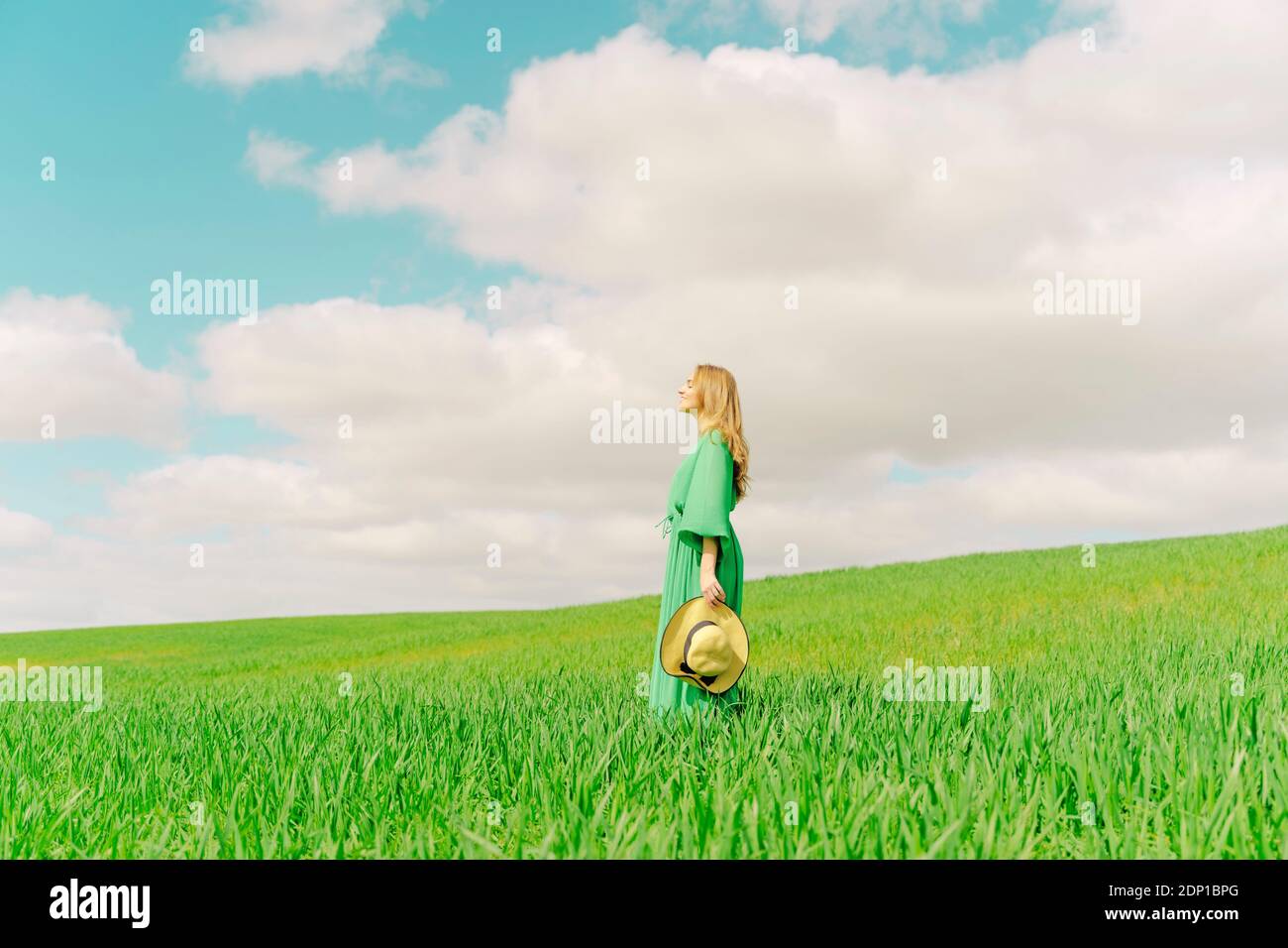 Blond young woman wearing green dress standing on a field Stock Photo ...