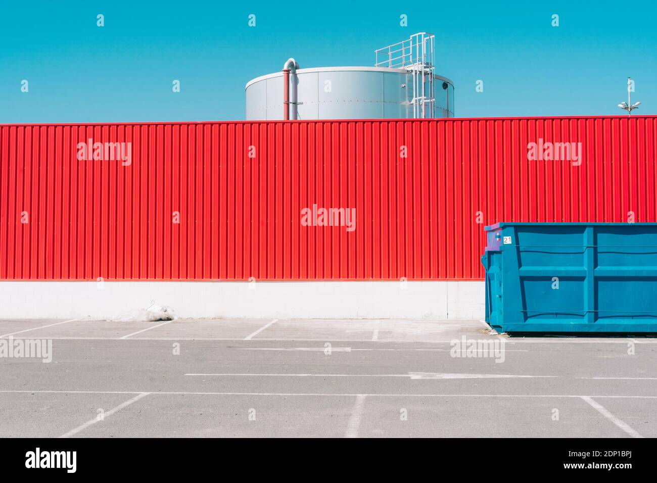 Blue container in front of red wall in industrial setting Stock Photo