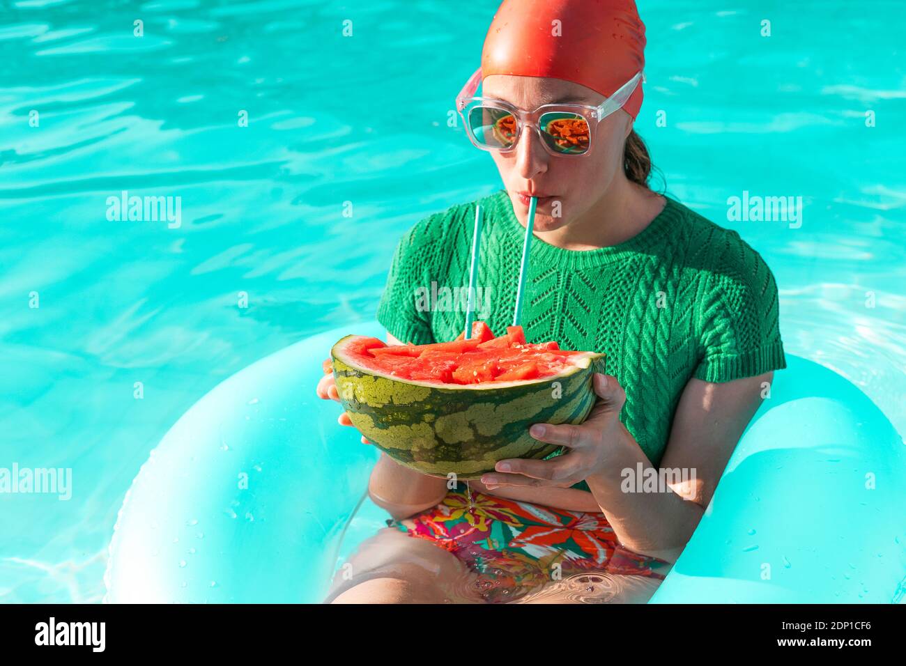 Portrait of woman with floating tire and watermelon in swimming pool Stock Photo