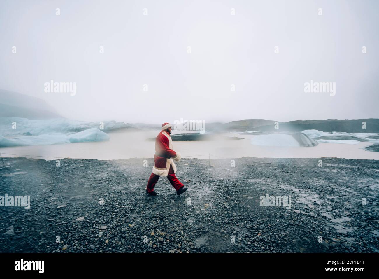 Iceland, Santa Claus walking in glacier landscape Stock Photo