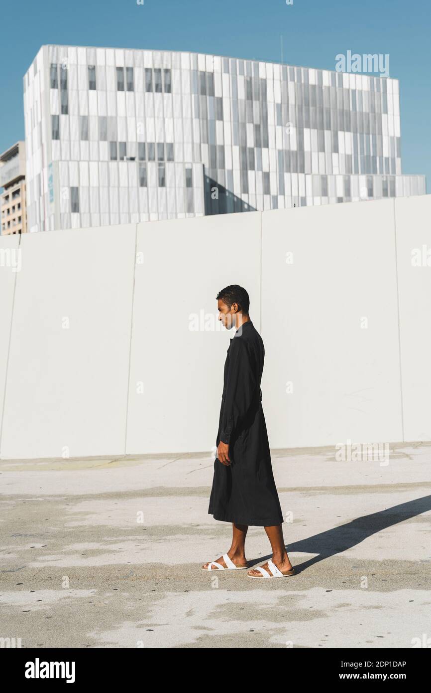 Young man wearing black kaftan standing outdoors Stock Photo