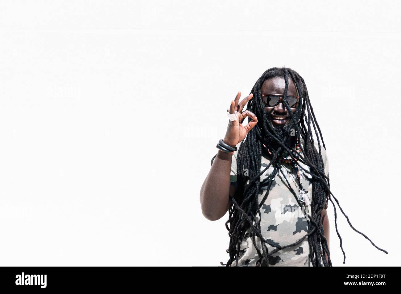 Smiling man with dreadlocks making positive hand sign Stock Photo