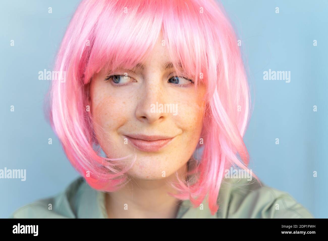 Portrait of young woman wearing pink wig glancing sideways Stock Photo