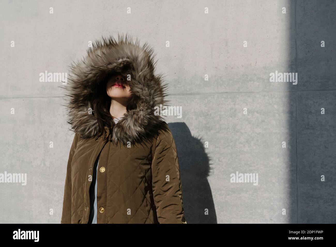 Portrait of anonymous woman with winter coat in the background of a wall Stock Photo