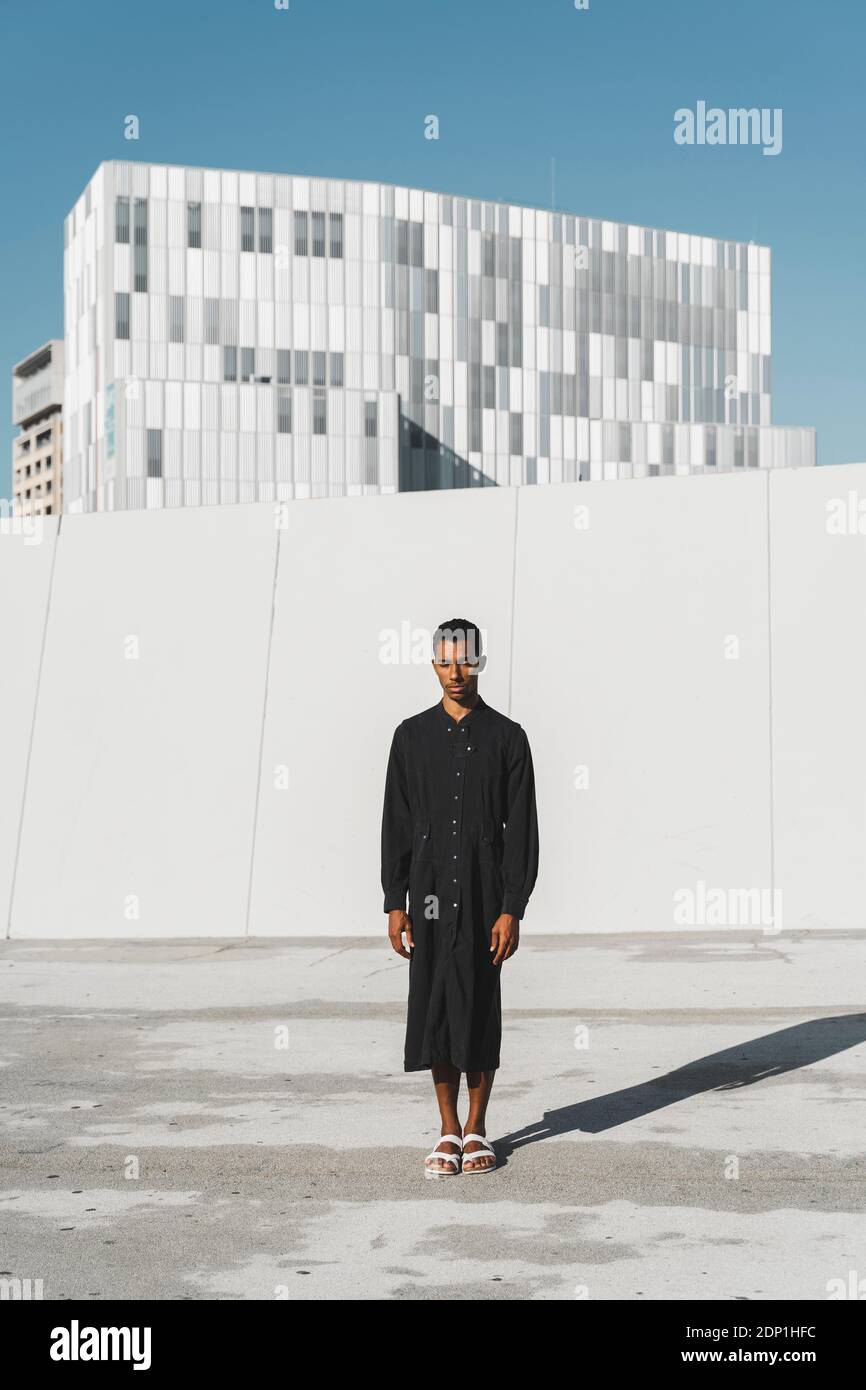 Young man wearing black kaftan standing outdoors Stock Photo