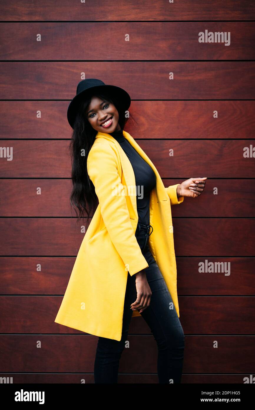 Portrait of smiling fashionable young woman posing at a wooden wall Stock Photo