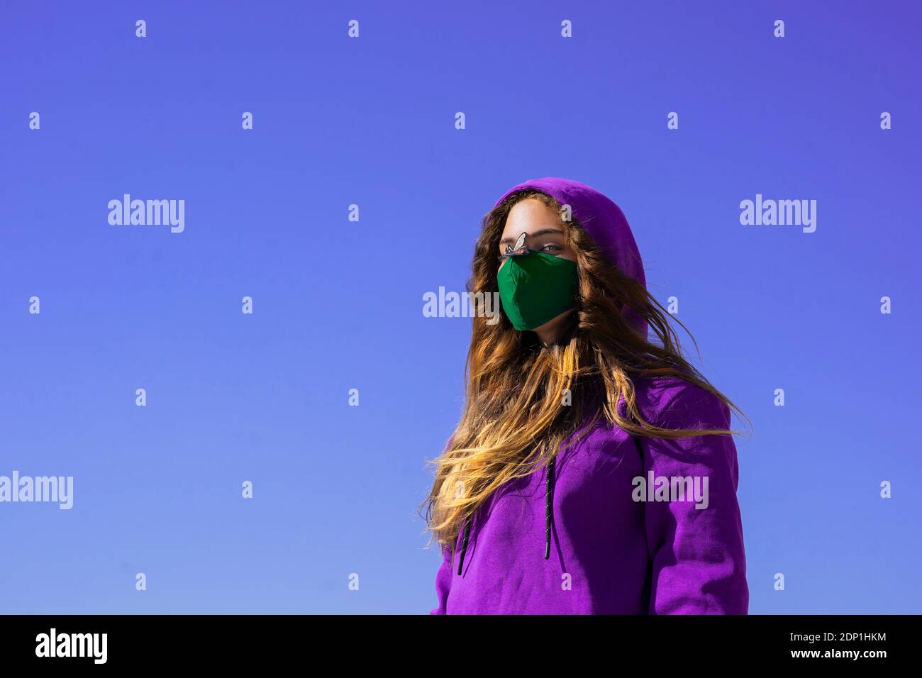 Teenage girl wearing hoodie and protective face mask with fly sticker on nose Stock Photo