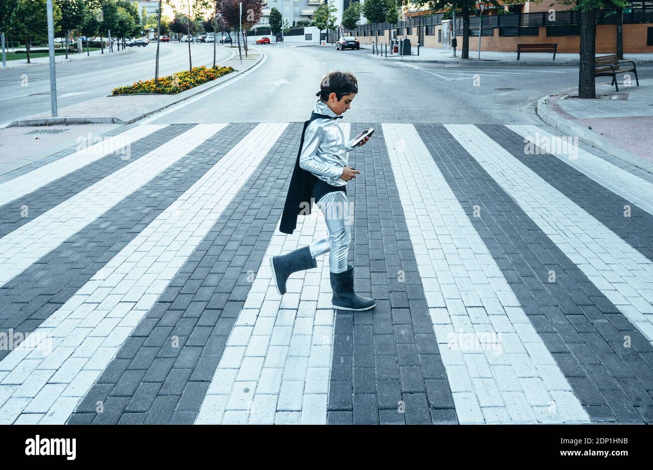 Portrait of boy disguised as superhero crossing a street the city Stock Photo