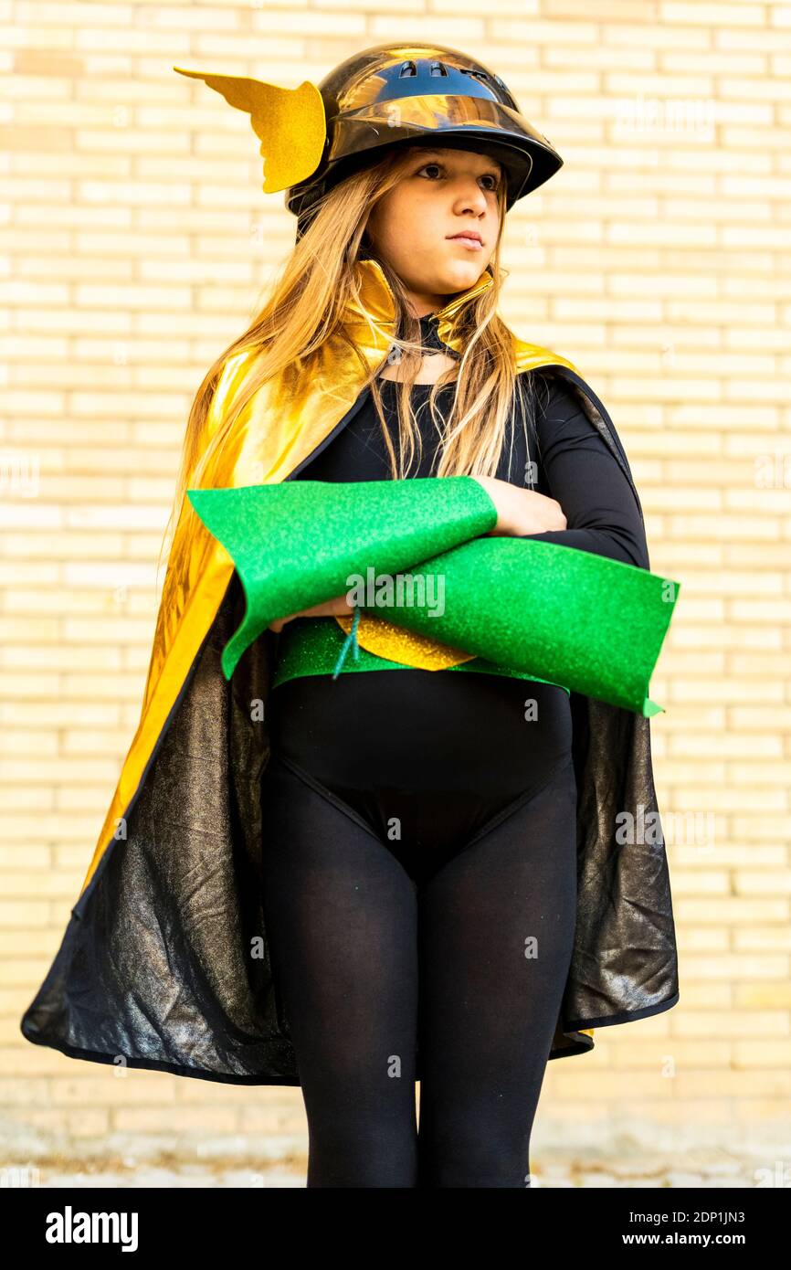 Girl in super heroine costume posing at brick wall Stock Photo