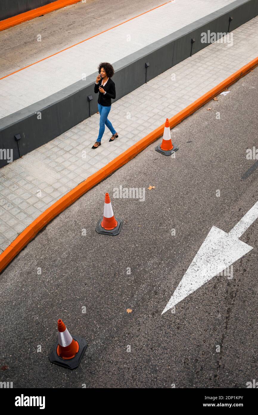 Businesswoman on the phone walking on pavement Stock Photo