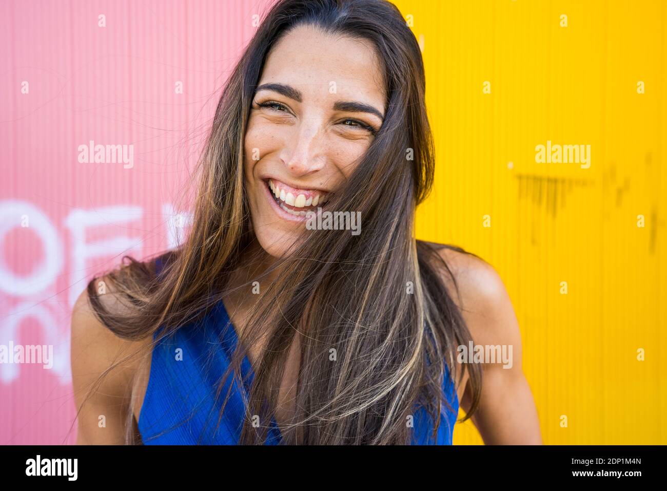 Young smiling woman in front of pink and yellow wall Stock Photo - Alamy