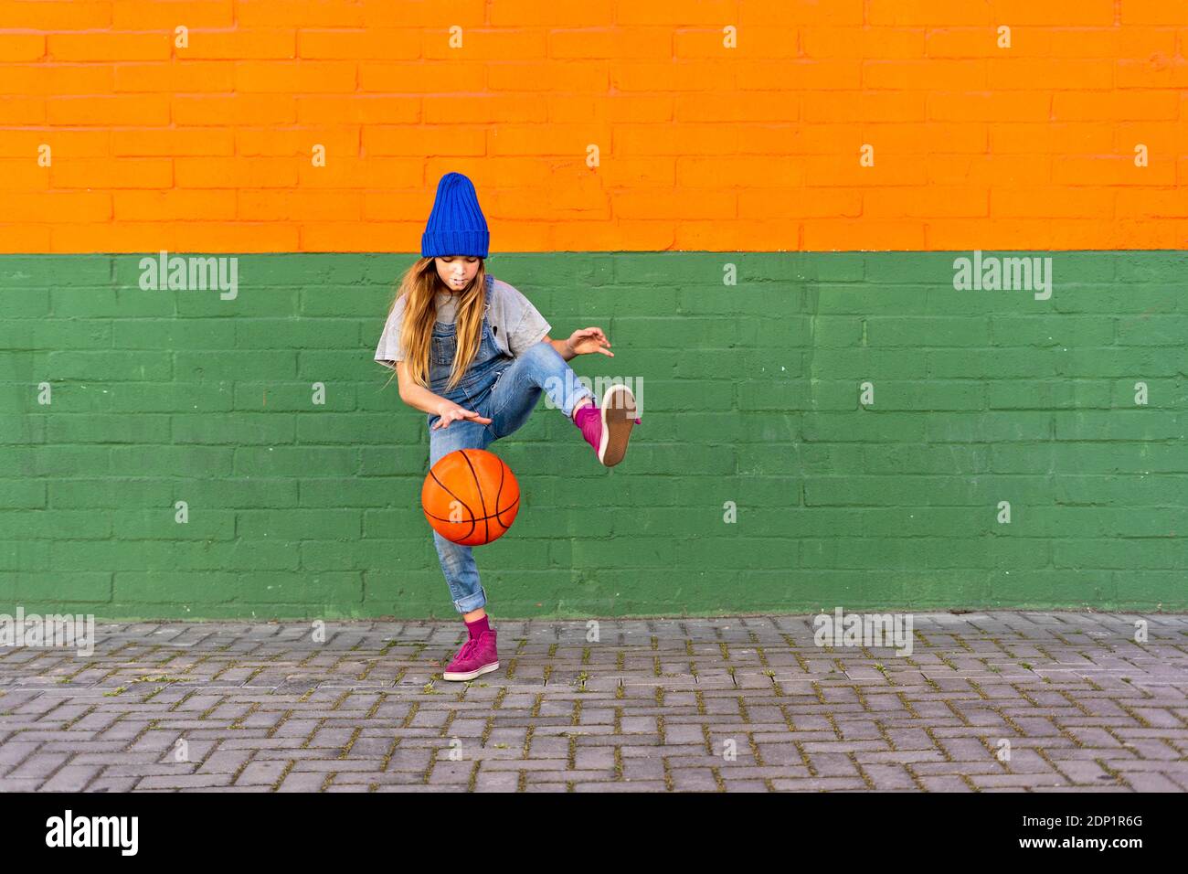 Young girl playing basketball, dribbling and lifting leg Stock Photo
