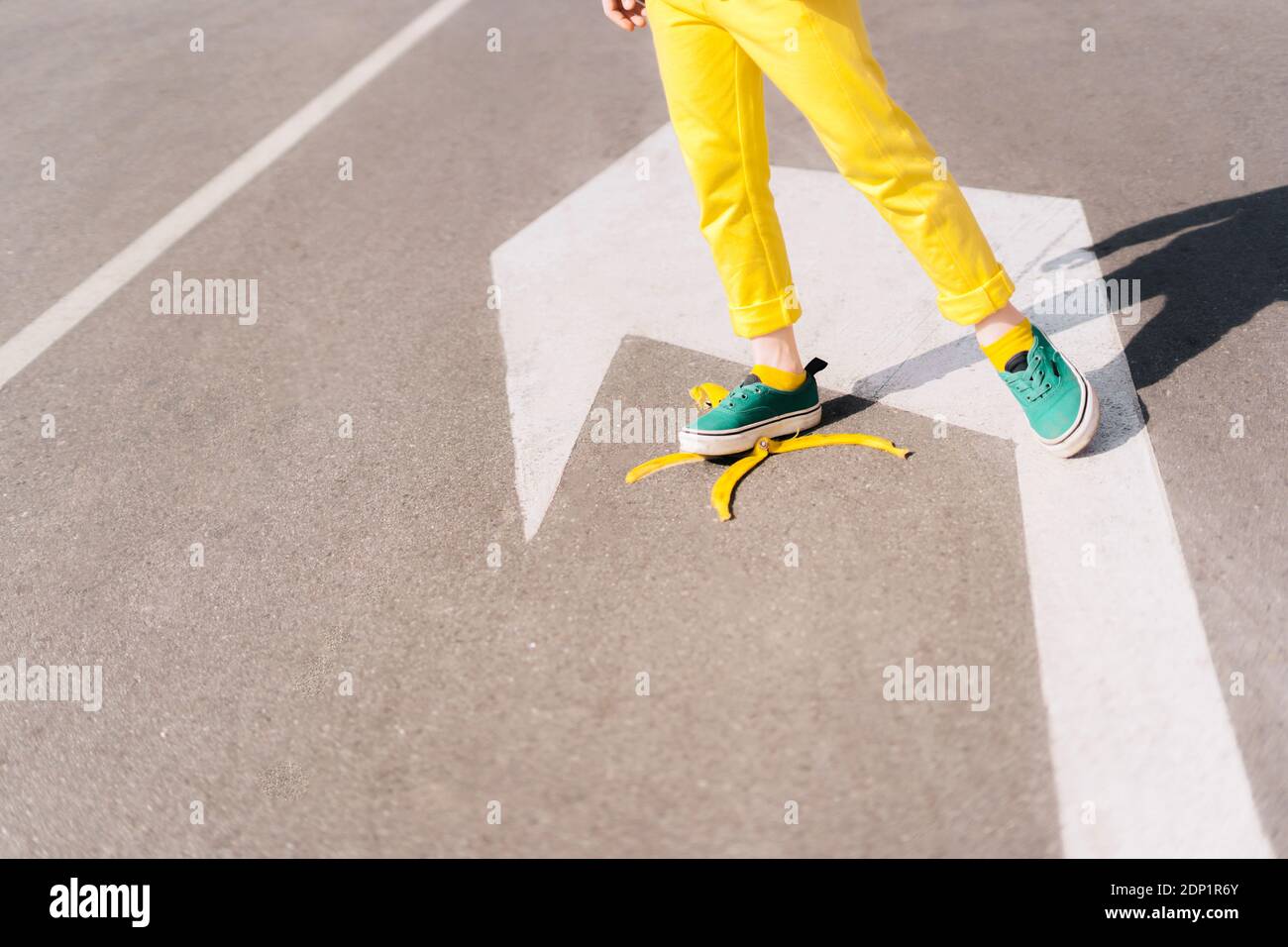 Girl stepping on banana peel on a street Stock Photo