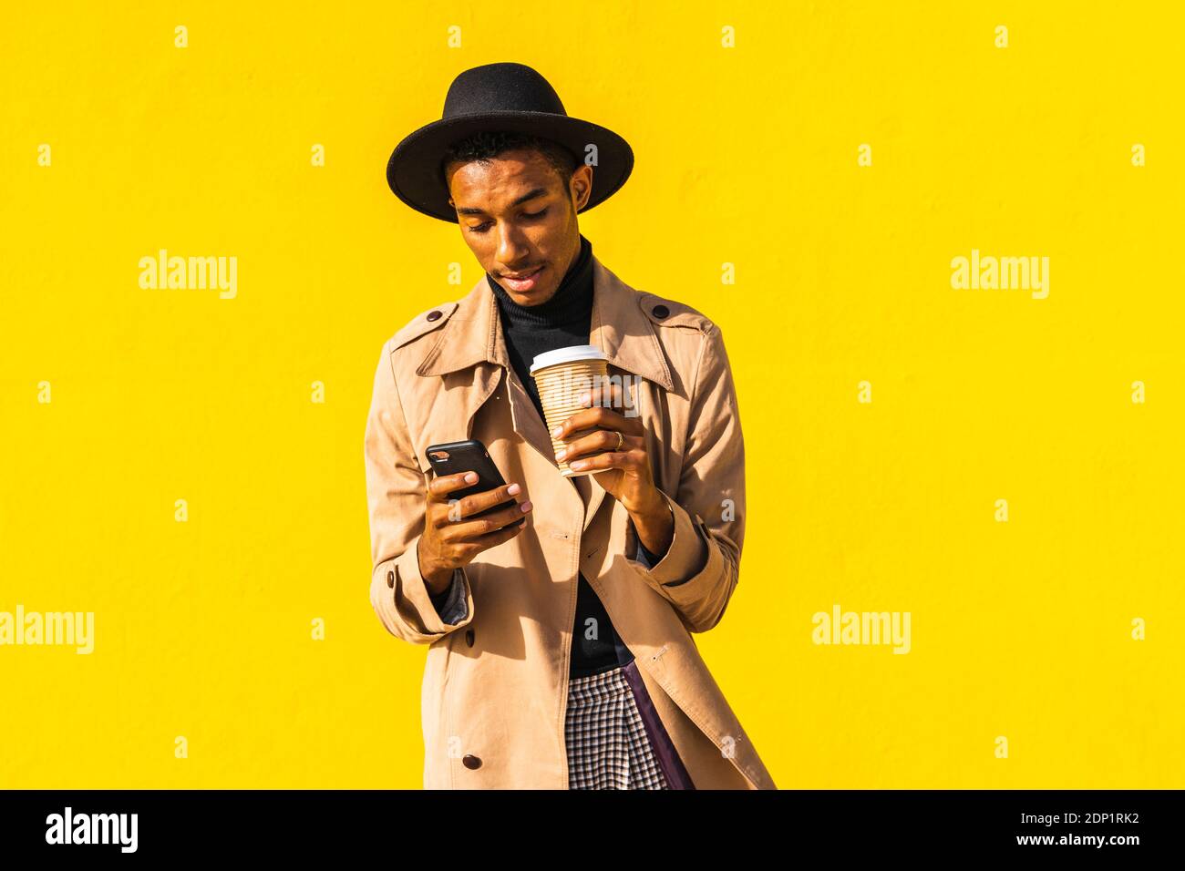 Young man with coffee cup, using smartphone Stock Photo