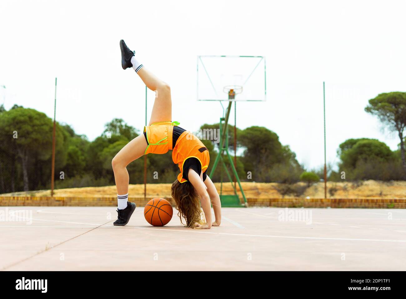 Teenage girl doing acrobatics on basketball ground Stock Photo