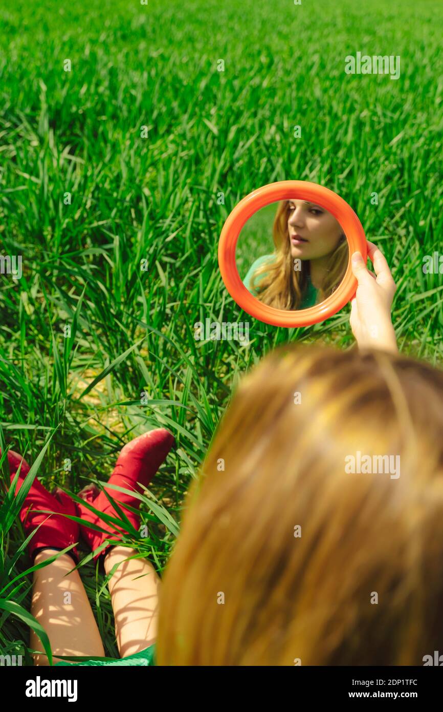 Mirror image of young woman sitting on a field Stock Photo