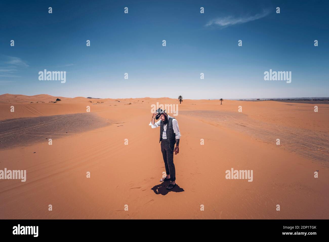 Man with a beard and hat in the dunes of the desert of Morocco Stock Photo