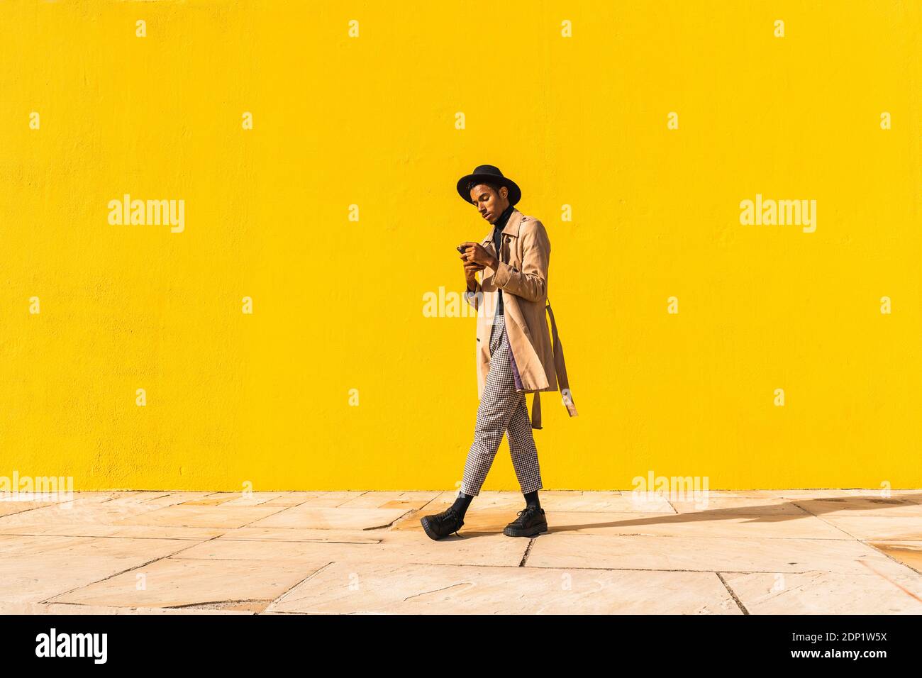 Young man with hat, using smartphone, drinking coffee Stock Photo