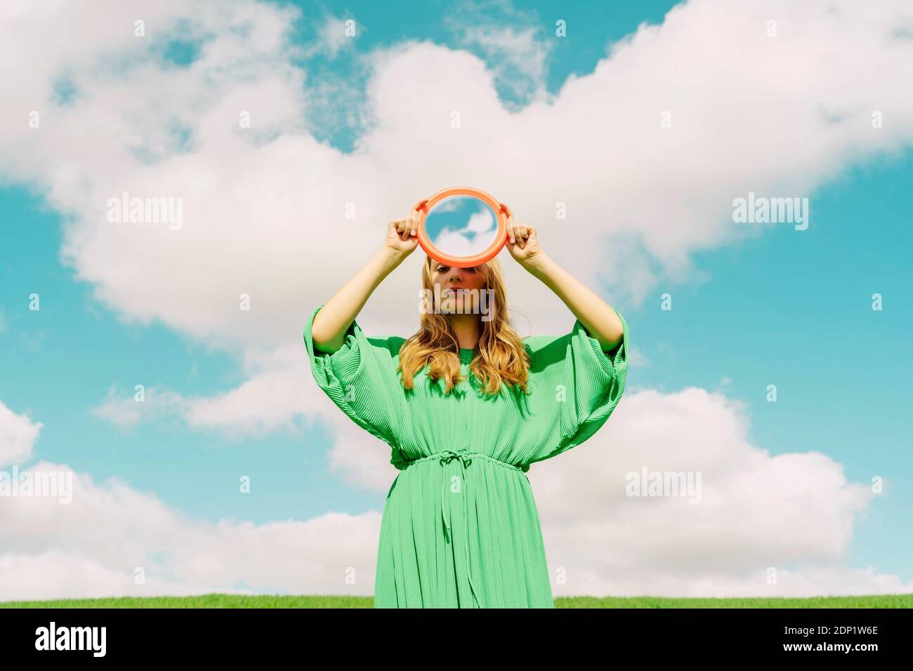 Young woman wearing green dress holding reflecting mirror Stock Photo ...