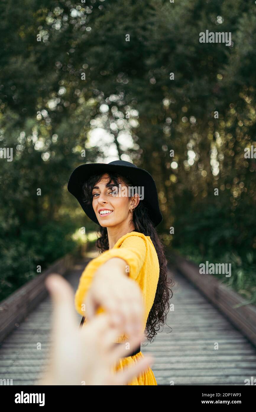 Young woman wearing a black hat and yellow dress and holding a hand Stock Photo