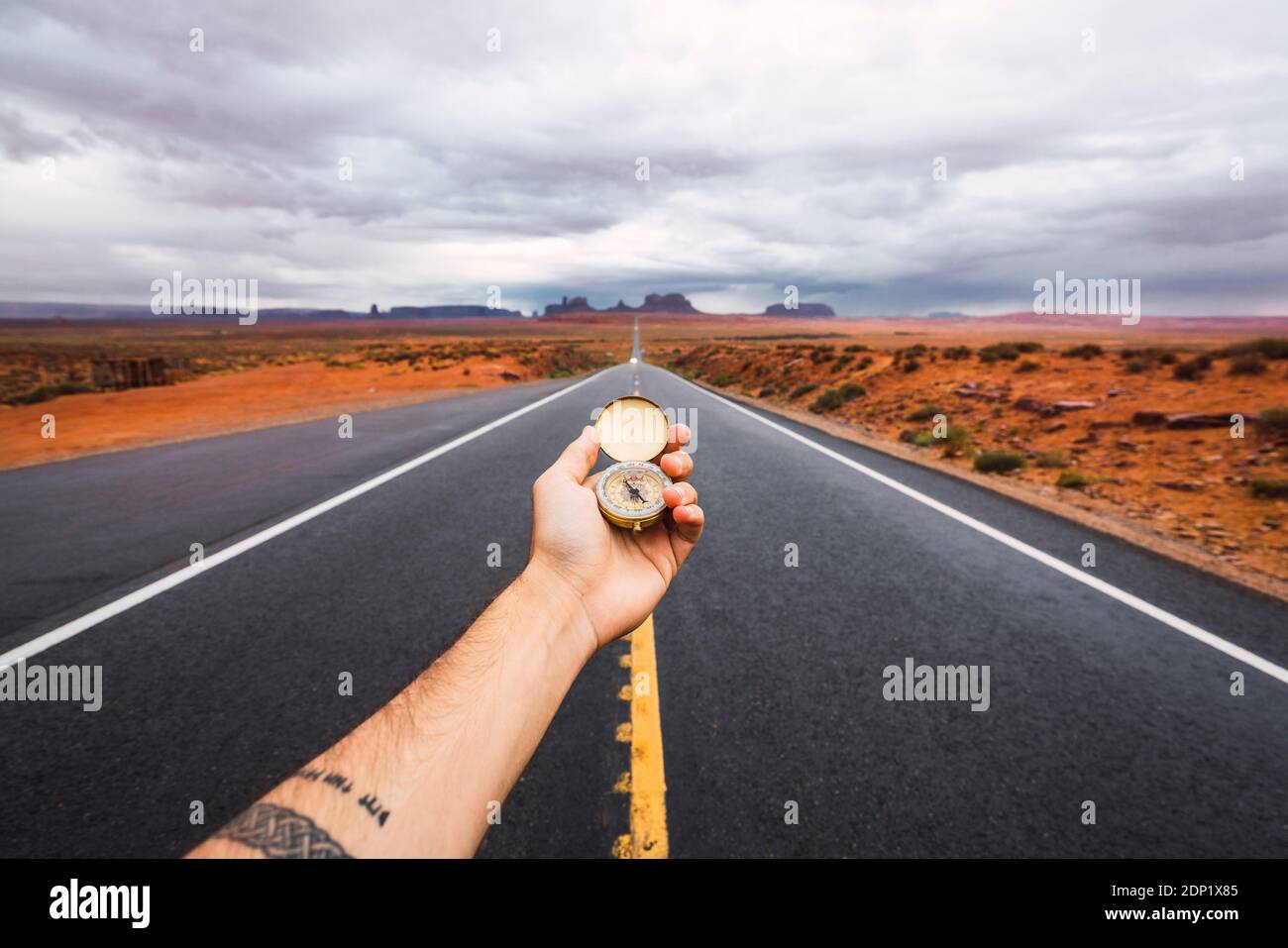 USA, Utah, Hand holding compass over road to Monument Valley Stock Photo