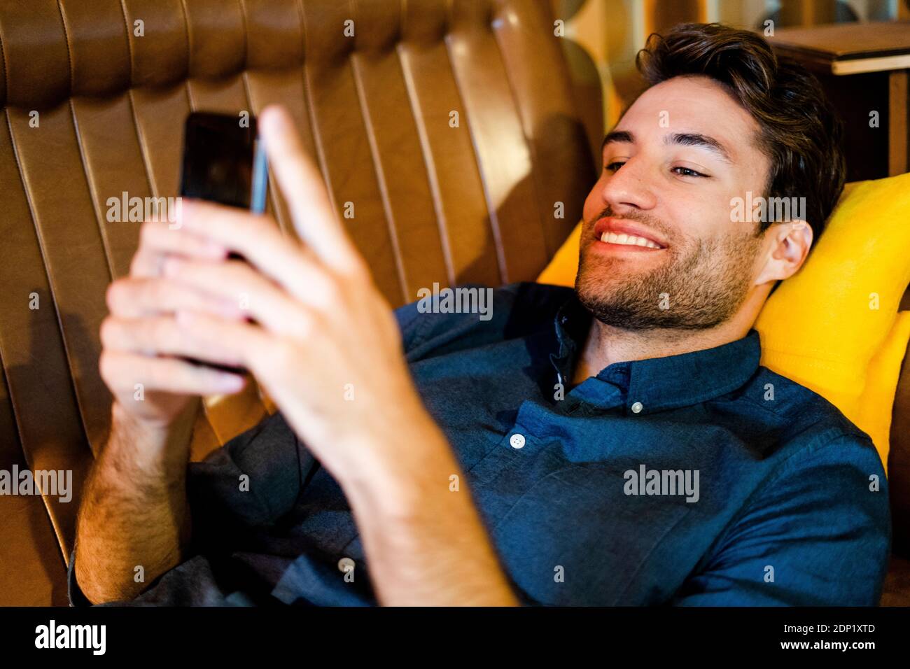 Man lying on couch using cell phone Stock Photo