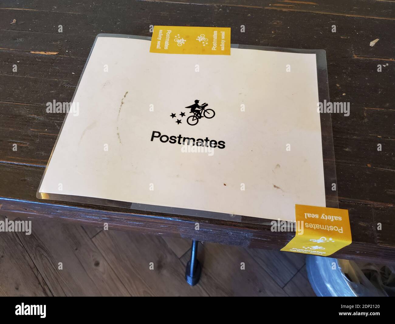 Photograph of a laminated placard featuring the the Postmates Delivery