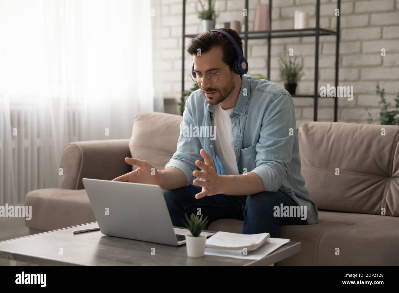 Young man teacher giving distant lesson in headset using pc Stock Photo
