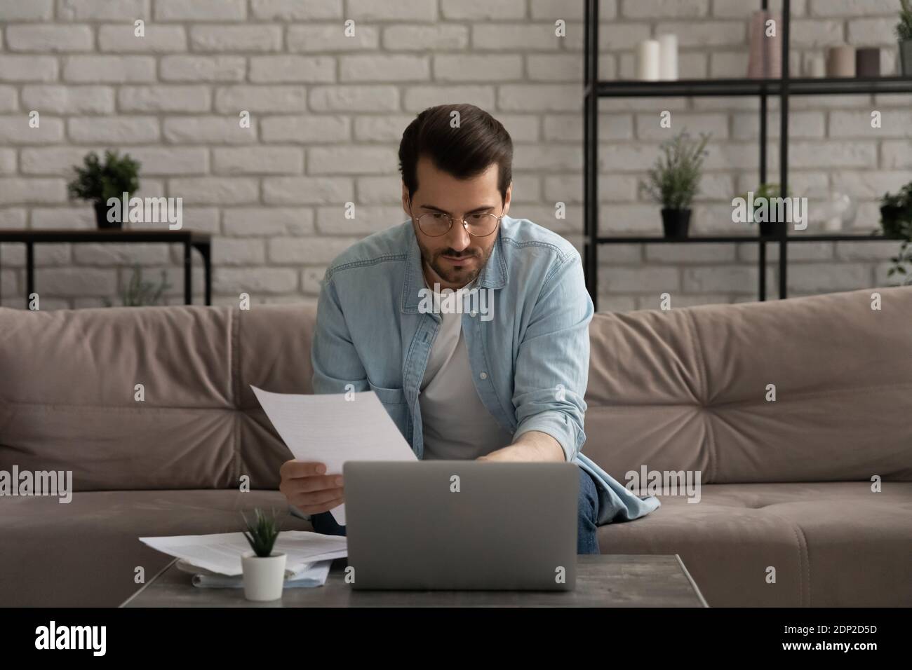 Serious thoughtful young man working with documents at home office Stock Photo