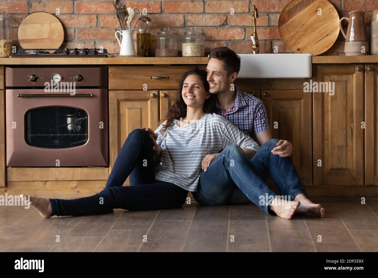 Happy newlyweds moving to new house creating plans at kitchen Stock Photo