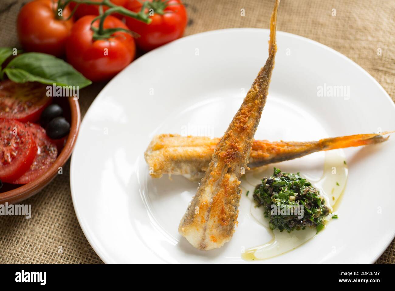 Two skinned tub gurnards, Cheliodonichthys lucerna, that have been rolled in flour and fried. They have been served with a herb, caper and black olive Stock Photo