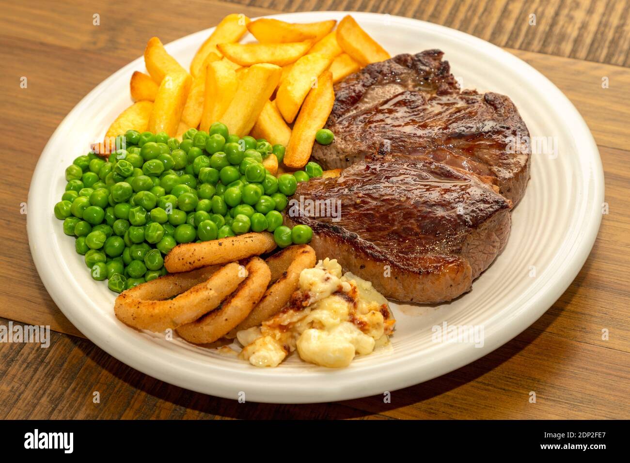 Steak Dinner - Rump steak, with chips, peas onion rings and cauliflower  cheese Stock Photo - Alamy