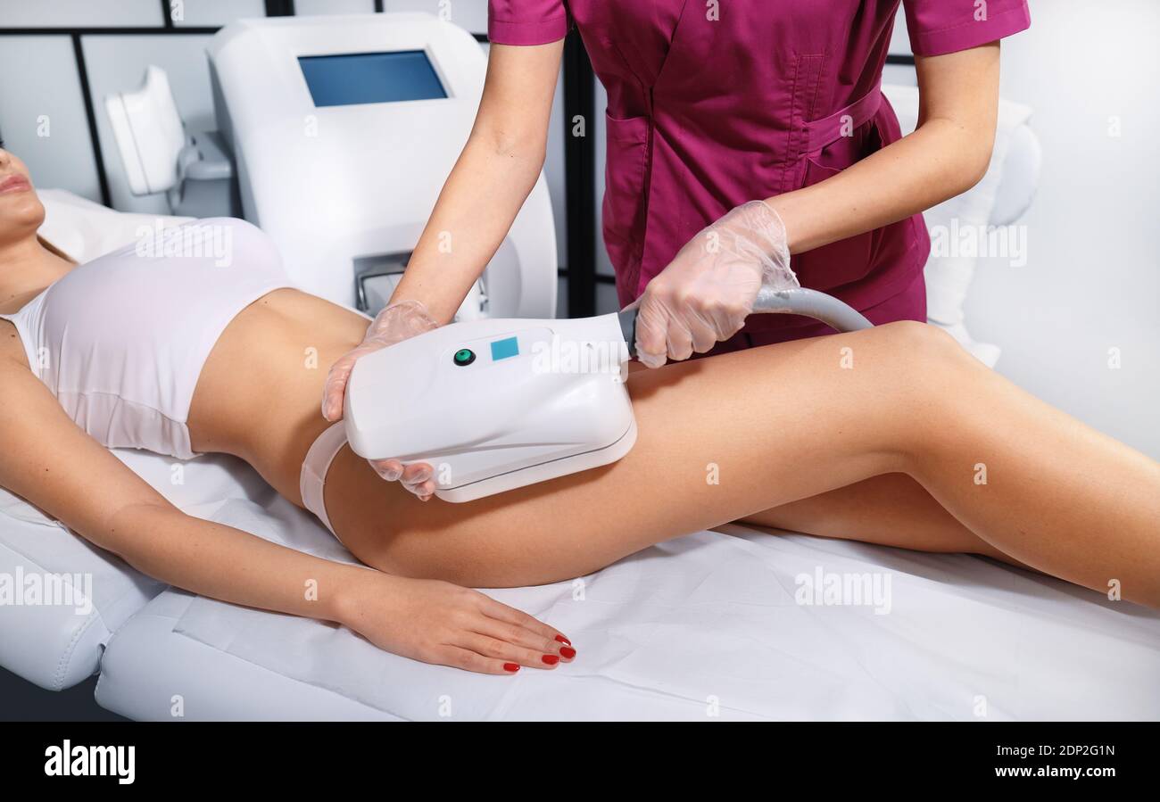Young woman getting cryolipolyse treatment in cosmetic cabinet. Cool sculpting procedure for slimming thighs. Body Fat freezing technology Stock Photo