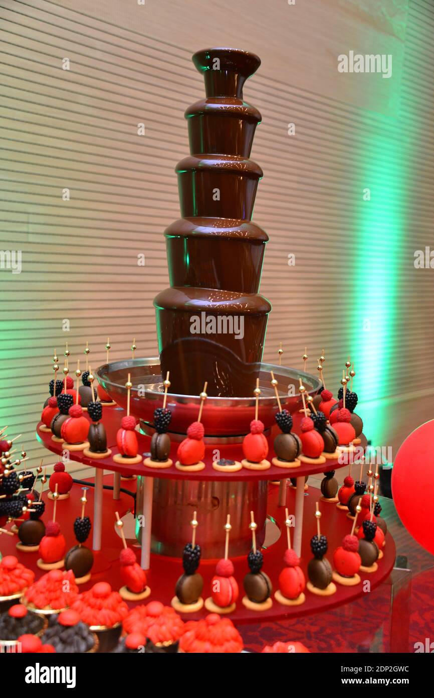 Chocolate fountain with red and black macarons. French sweet Stock
