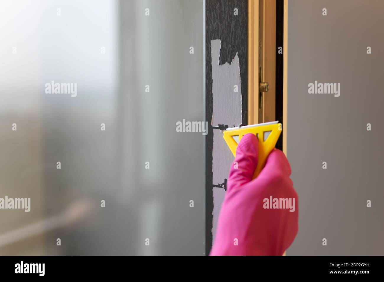 Removing protective tape from the window frame with scraper Stock Photo