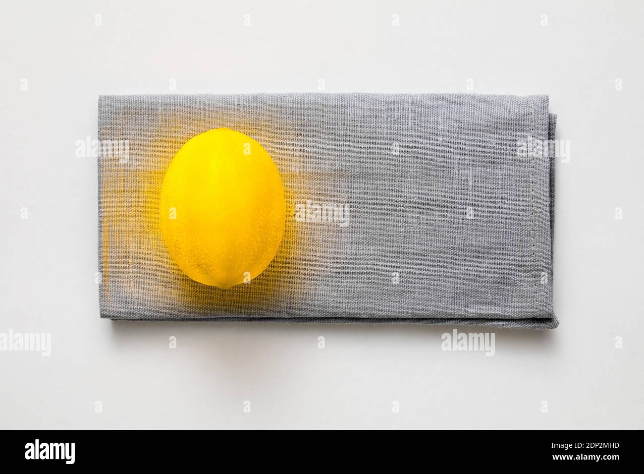 Color of the year 2021 creative concept. Yellow illuminating lemon on gray linen napkin Stock Photo