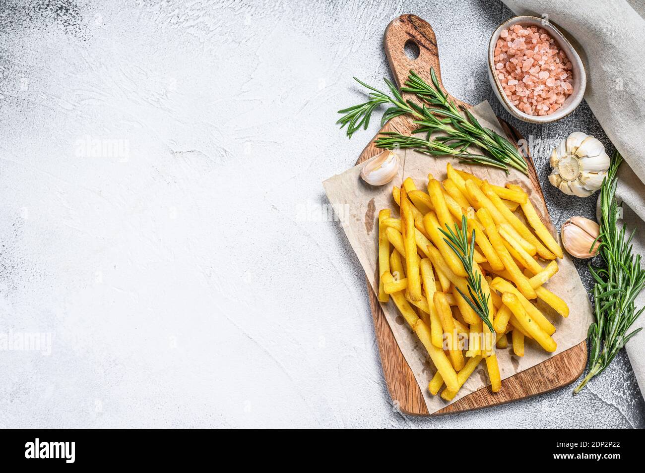 Potatoes fries, French fries with rosemary on a cutting board. White