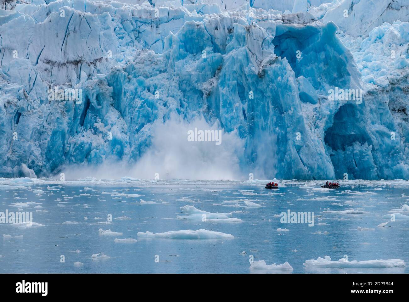 Guests from a cruise ship in Zodiac inflatable boats observer a tidewater glacier calving close up in Alaska. Stock Photo