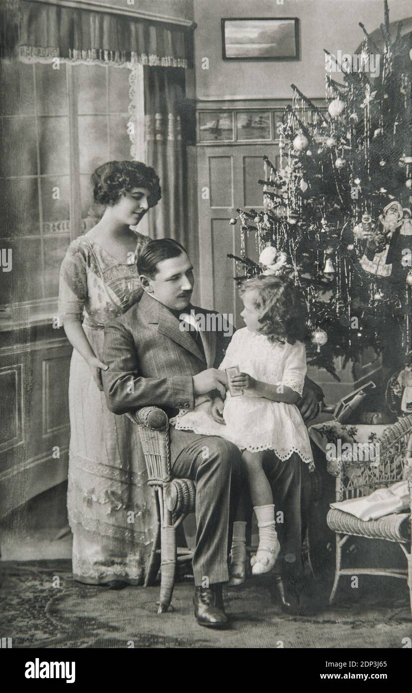 Victorian family parents and daughter with Christmas tree. Vintage picture with original film grain and blur Stock Photo
