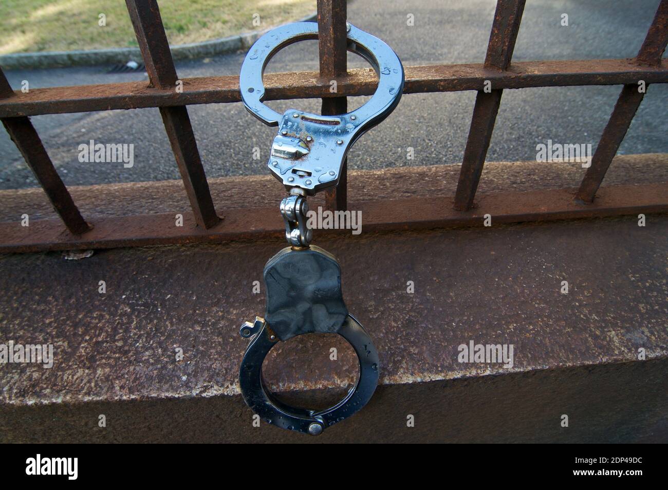 Handcuffs device hanging on a rusty railing Stock Photo