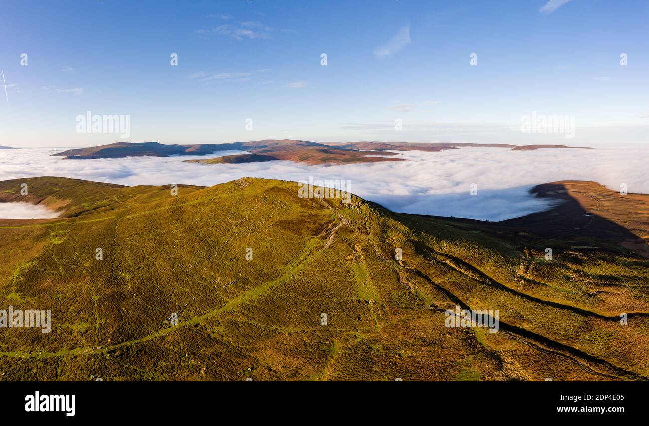 Panoramic aerial view of a mountain summit rising above a sea of low cloud and fog (Sugar Loaf, Wales). Stock Photo