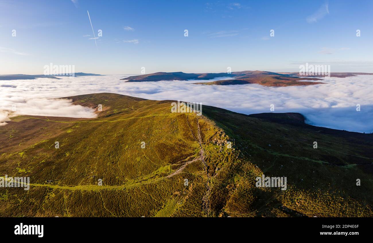 Panoramic aerial view of a mountain summit rising above a sea of low cloud and fog (Sugar Loaf, Wales). Stock Photo