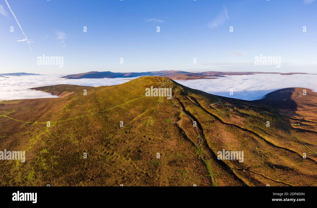 Panoramic aerial view of a mountain summit rising above a sea of low cloud and fog (Sugar Loaf, Wales). Stock Photo
