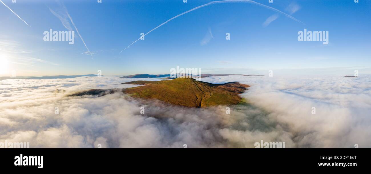 Panoramic aerial view of a mountain summit rising above a sea of low cloud and fog (Sugar Loaf, Wales). Stock Photo