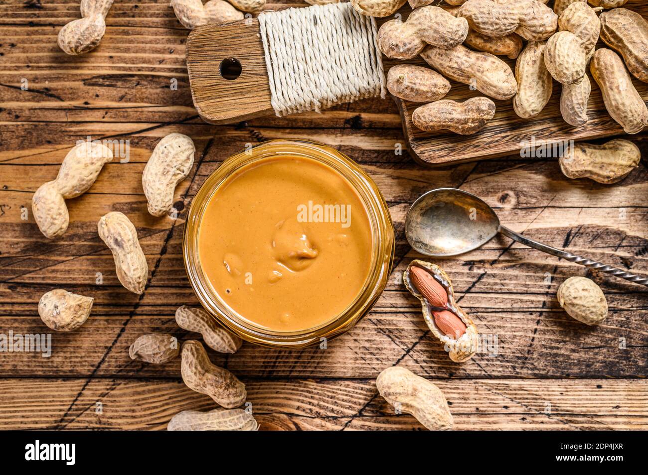 https://c8.alamy.com/comp/2DP4JXR/fresh-made-creamy-peanut-butter-in-a-glass-jar-wooden-background-top-view-2DP4JXR.jpg